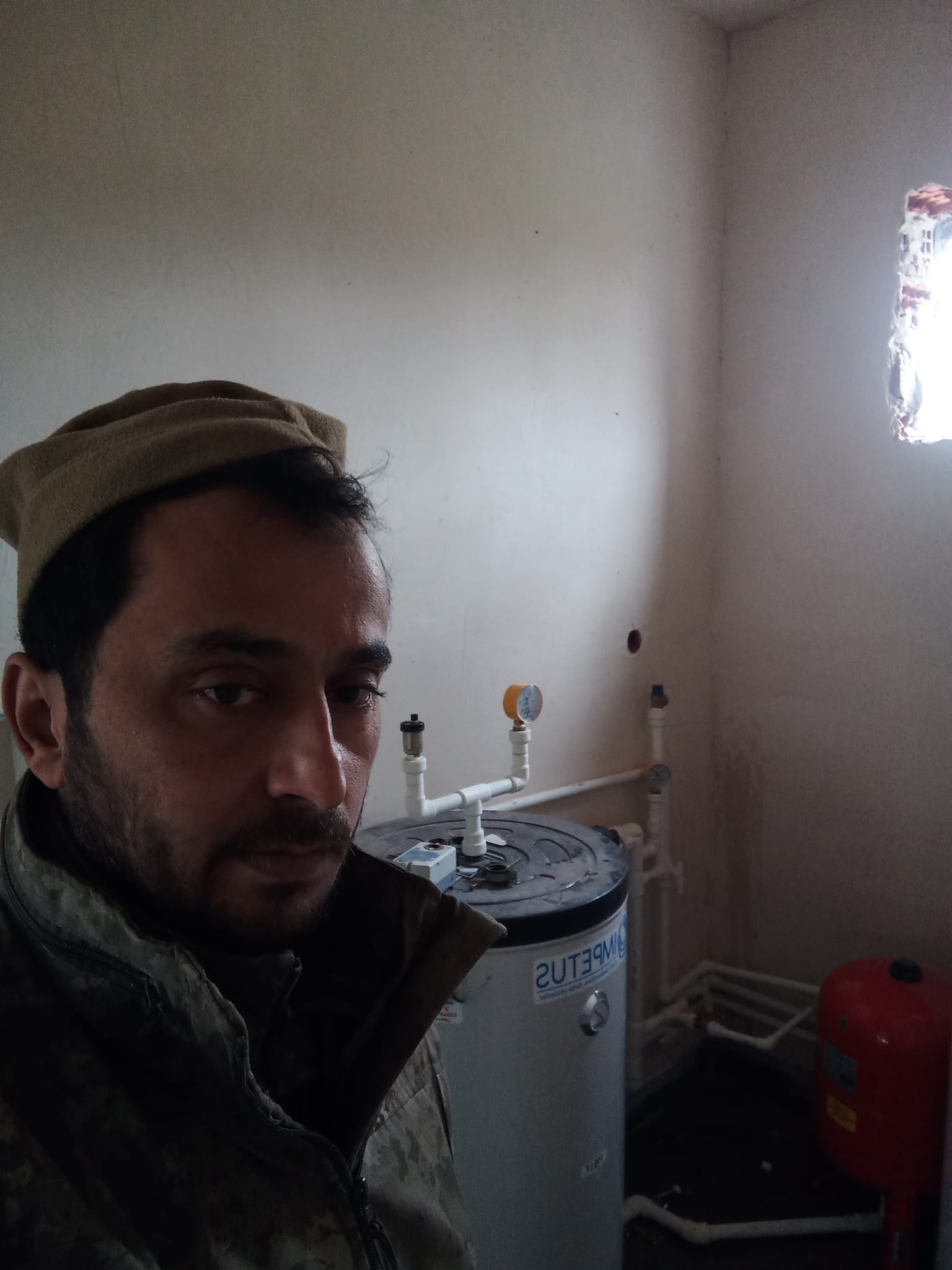 Isı pompası tankı ve genleşme tankı önünde kurulum yapan tesisat ustası