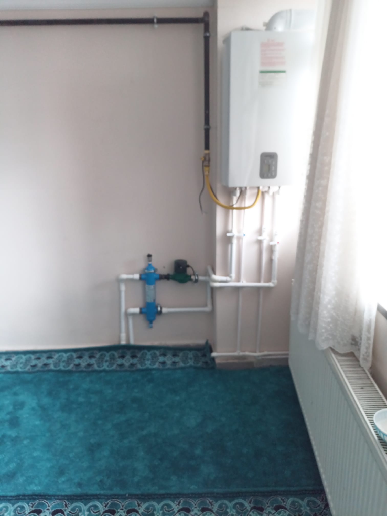 Duvara monte kombi, sarı doğal gaz hattı, su boruları ve radyatör bağlantıları
